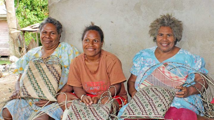 Women proudly displaying their woven bags